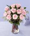 
They will be charmed by this gift of a dozen pink roses in a glass vase, surrounded by assorted greenery...
			